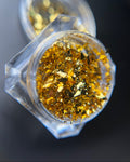 Hexagonal container with gold flake powder and 'prisma nail store' branding.